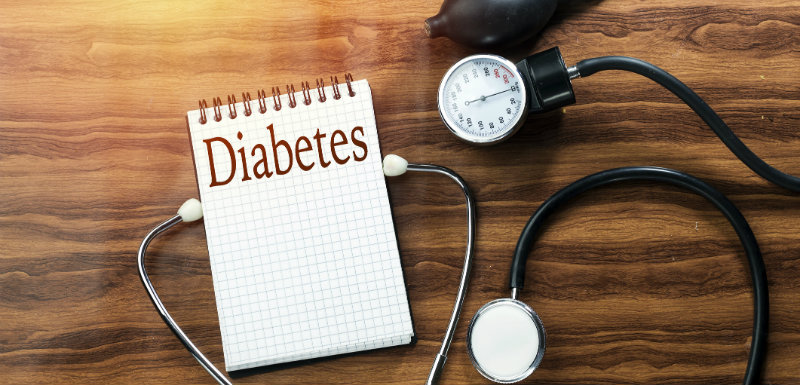 texte diabète épidémiologiques écrit sur un cahier blanc qui se trouve sur une table en bois et un stéthoscope noir